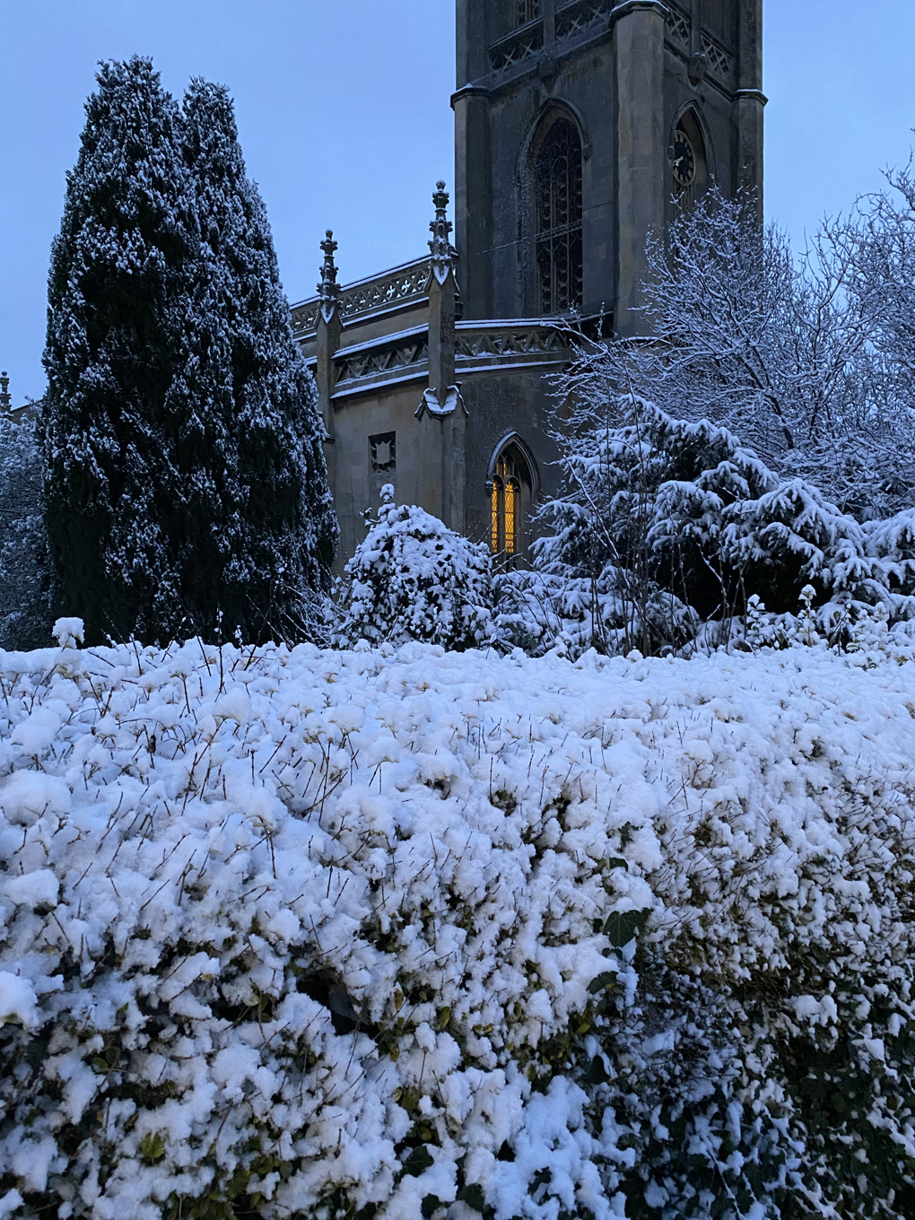 A church with a lit up window against a snowy background