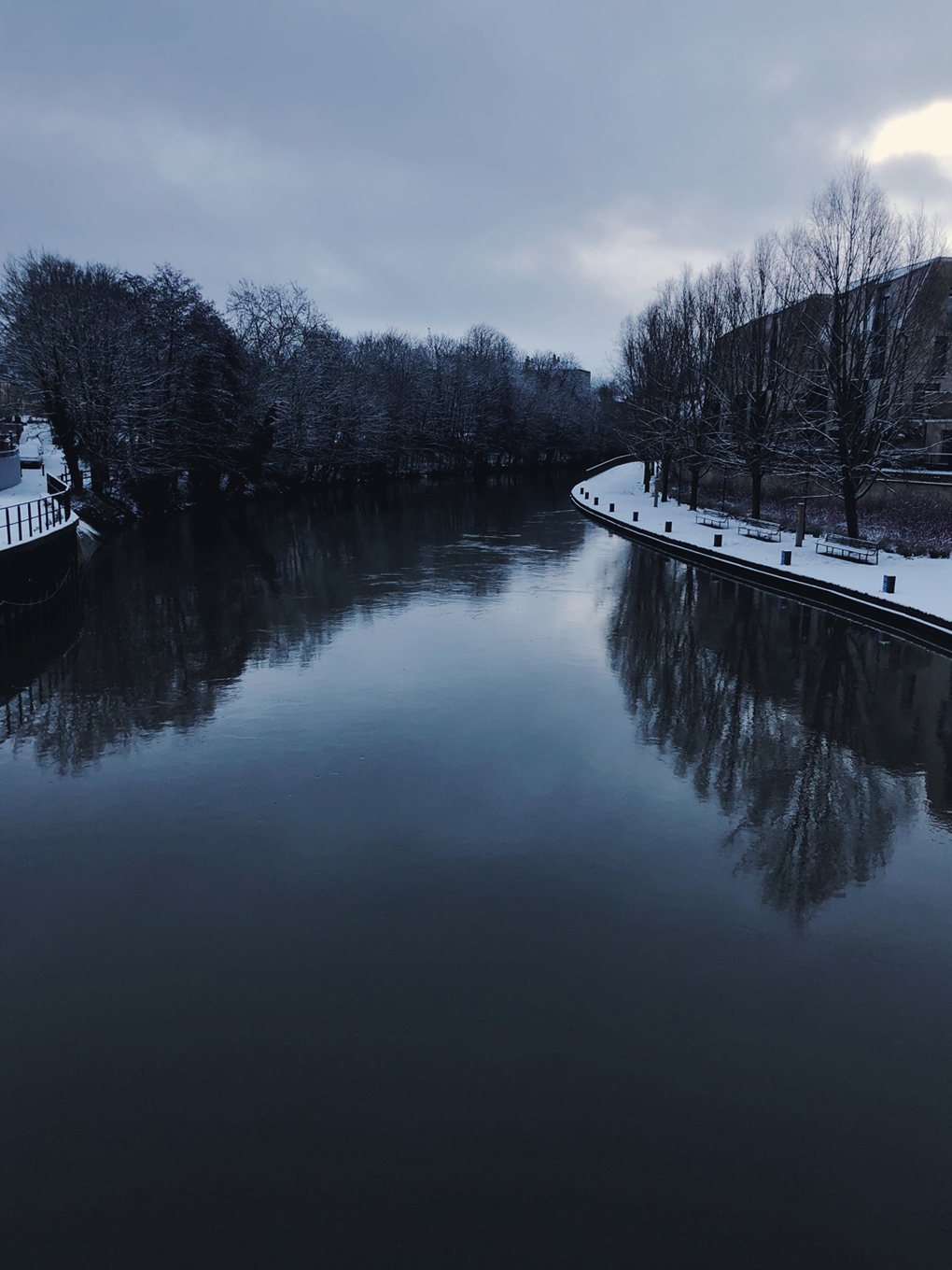The a view from Victoria Bridge of the River Avon hemmed in by snow-laden paths.