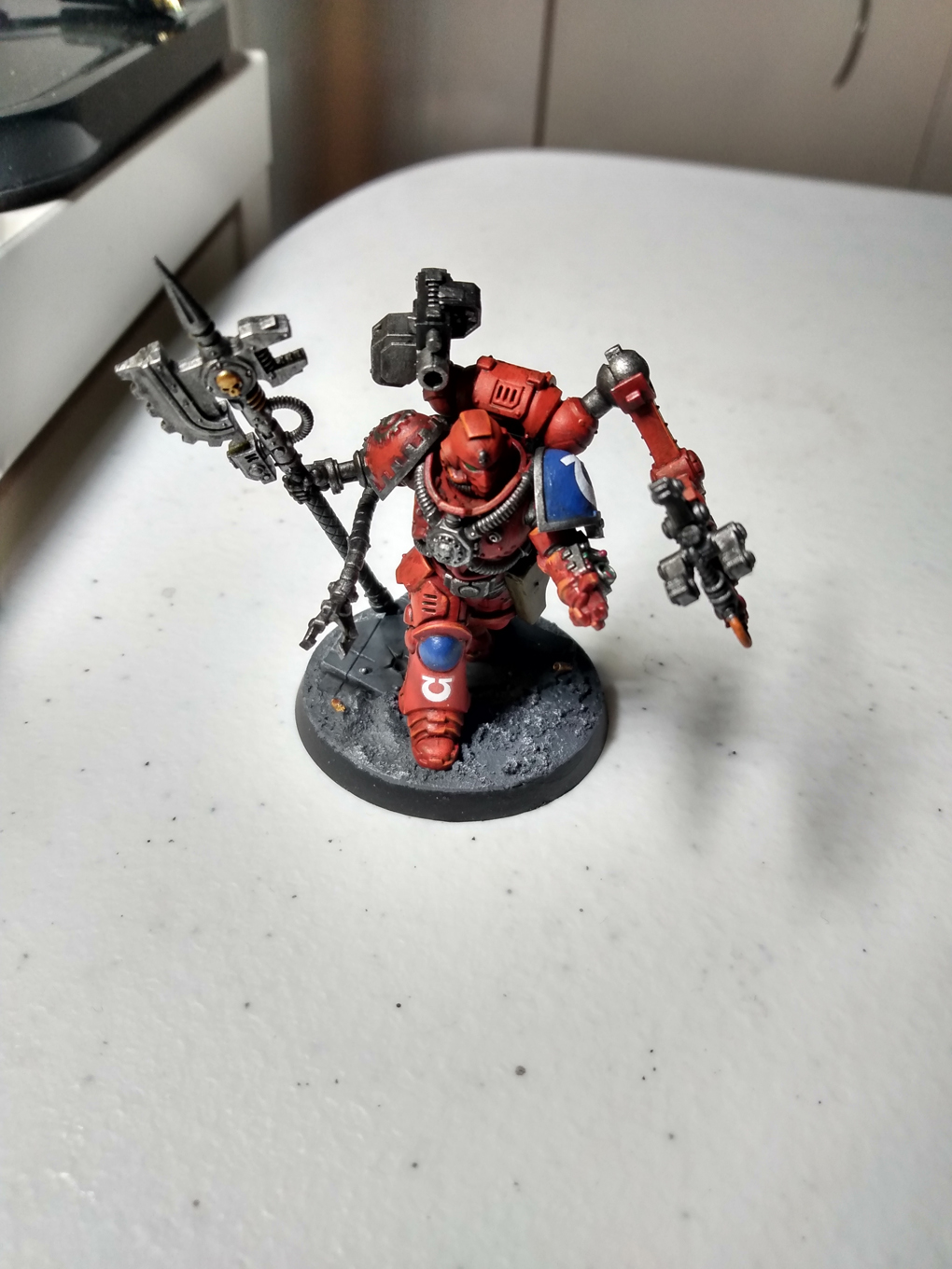 A red armoured space marine miniature sits of a table