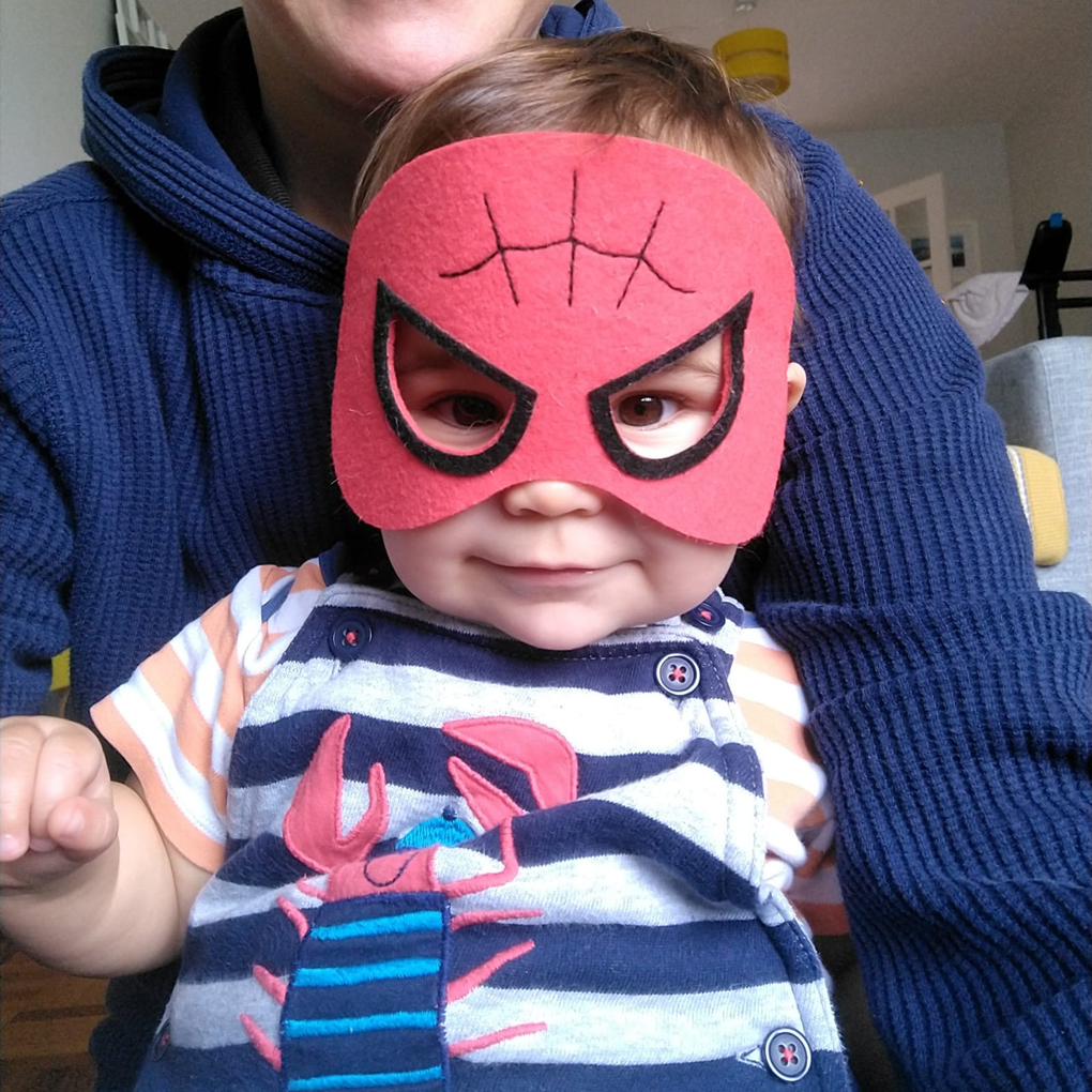 A baby wearing a Spiderman mask