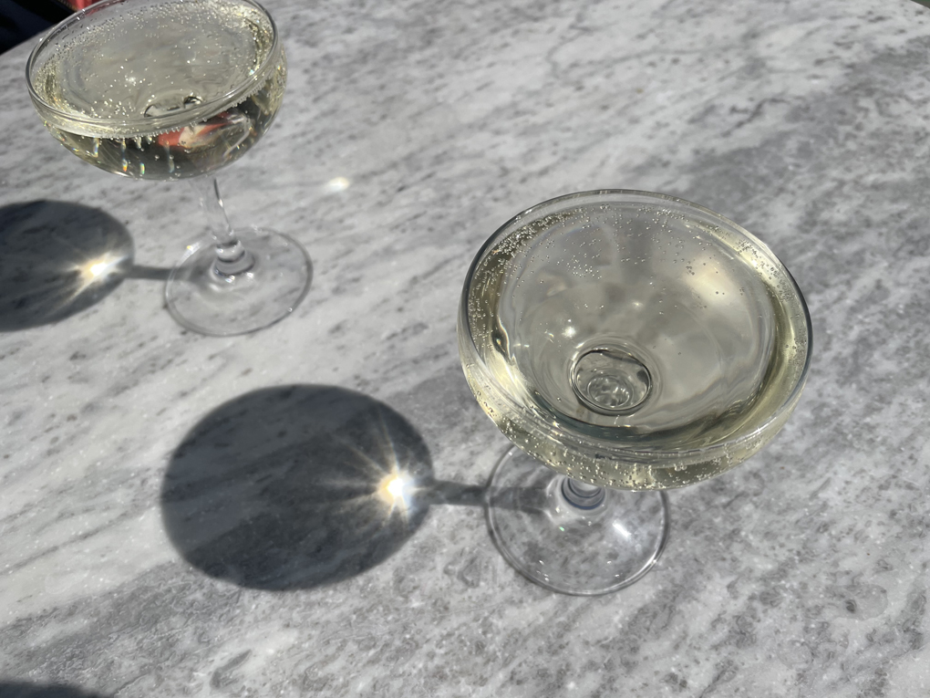 Champagne coupes on a marble table in the sun