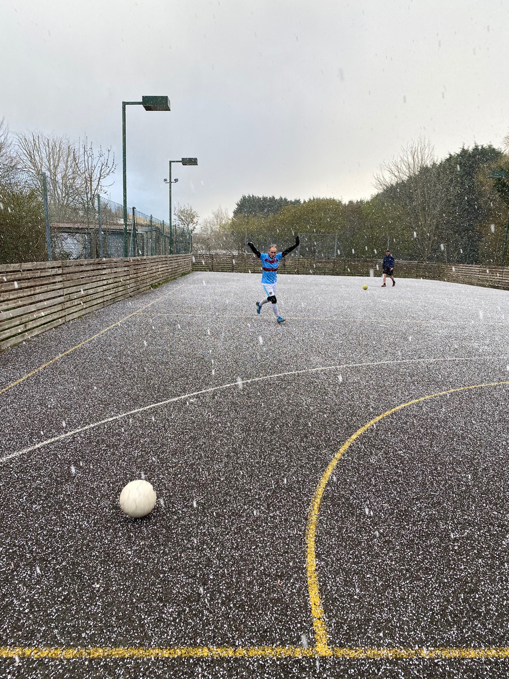 A footballer celebrating a successful shot on goal during a blizzard