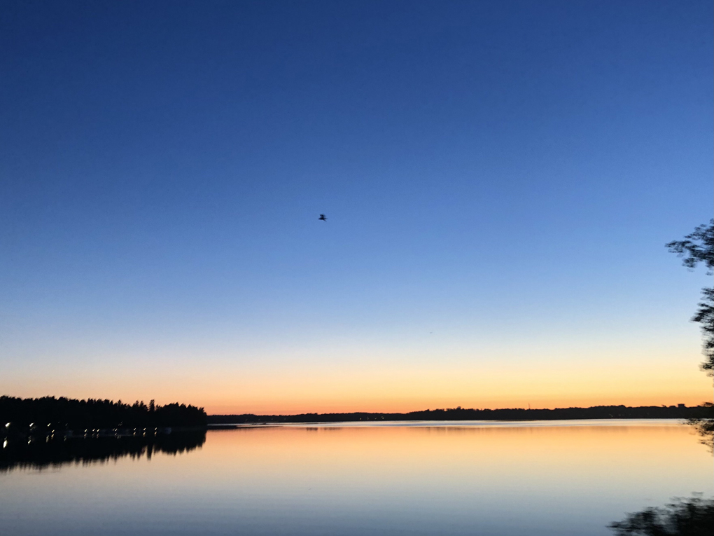 Sun rising in the horizon behind water