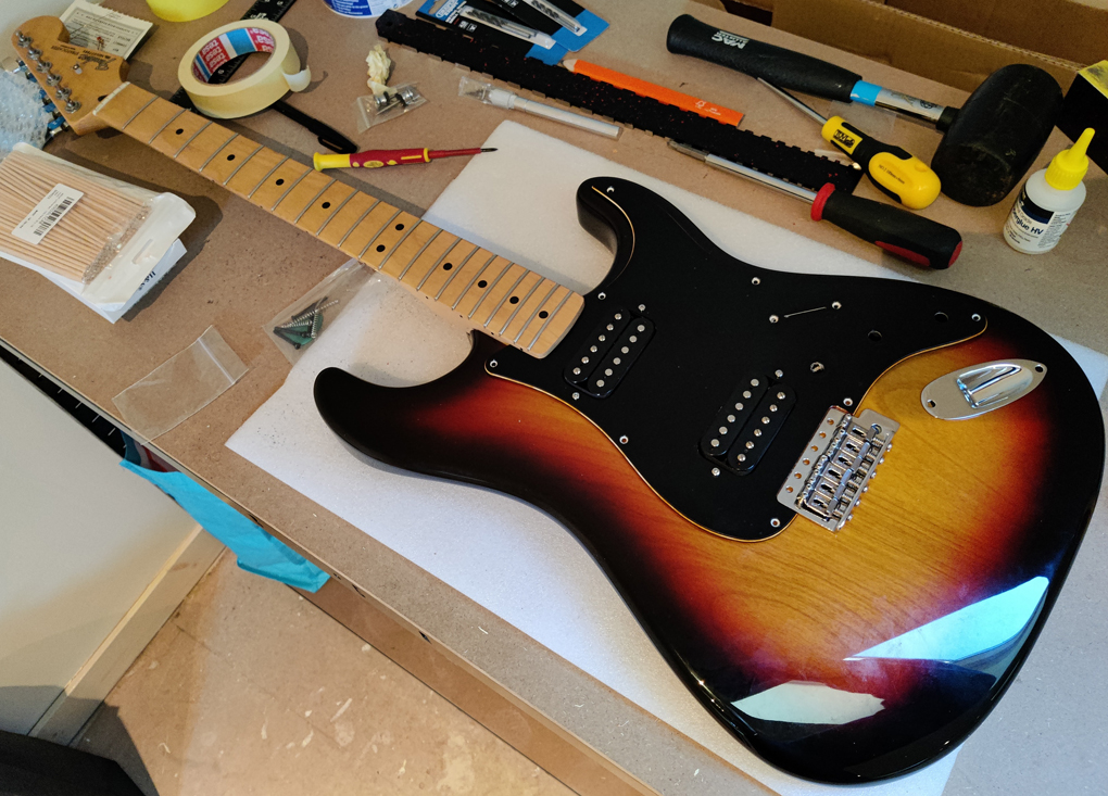 A part-built sunburst and black Fender Stratocaster on a workbench