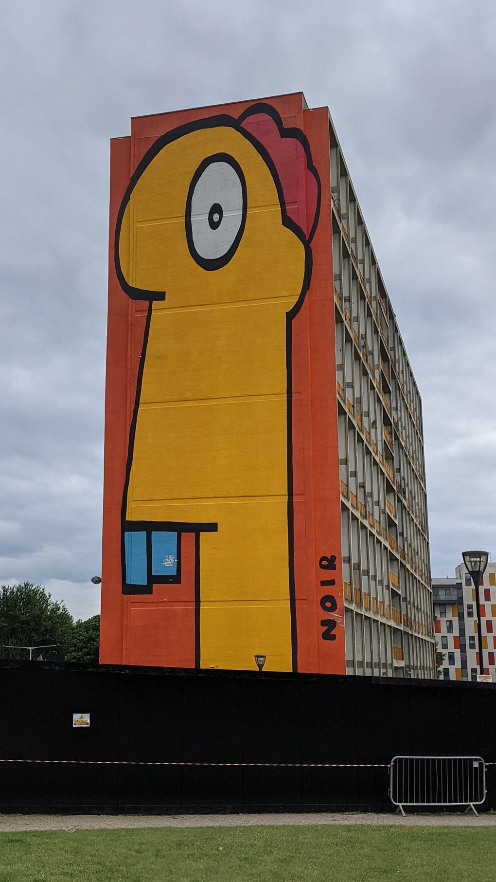 An enormous cartoon character with large teeth painted on the side of a block of flats.