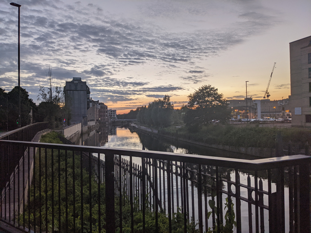 Sunset over the river Avon in Bath. Mix of urban building, greenery along the river and water mirroring the sky