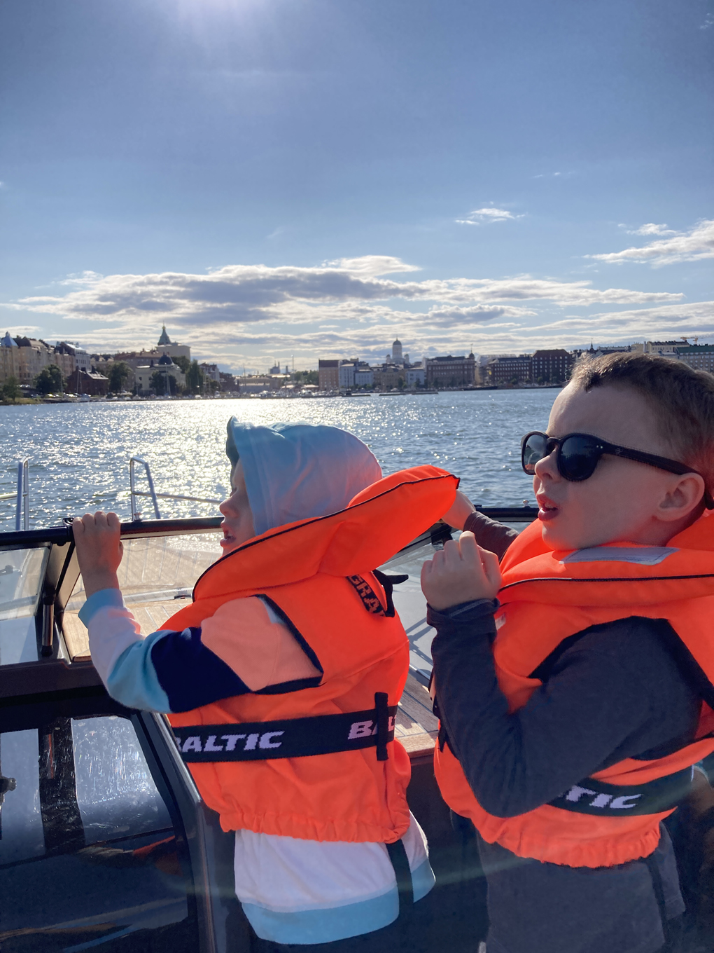 Two boys wearing life vests in a boat.