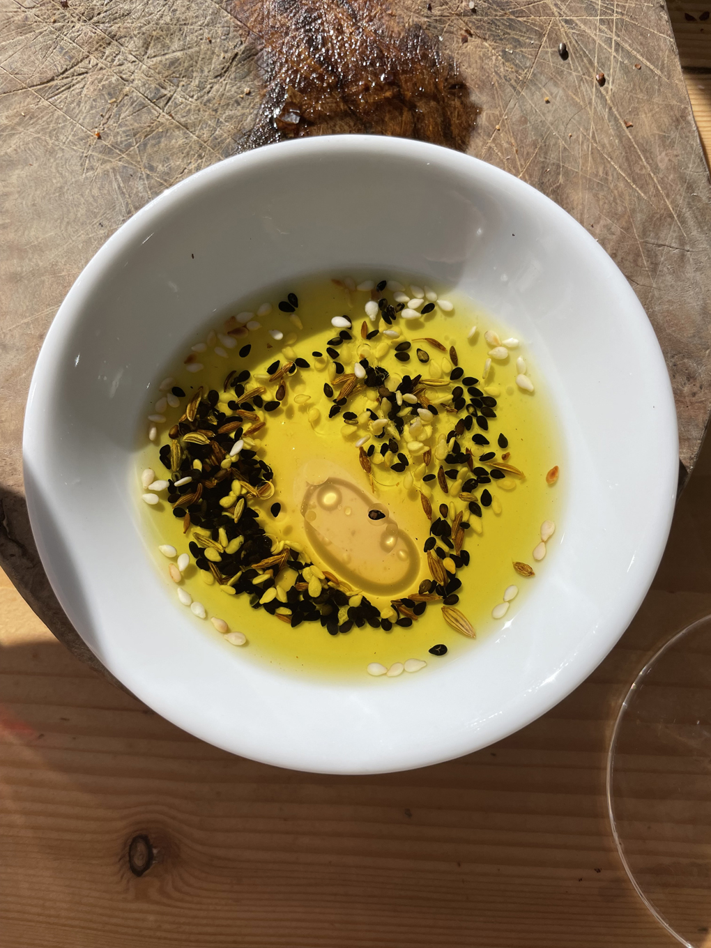 Wooden bread board with dish containing olive oil and seeds