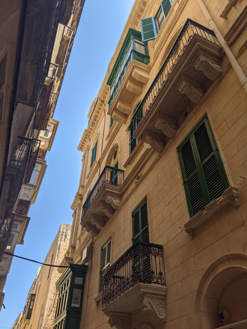 Looking up towards buildings, balconies and sky