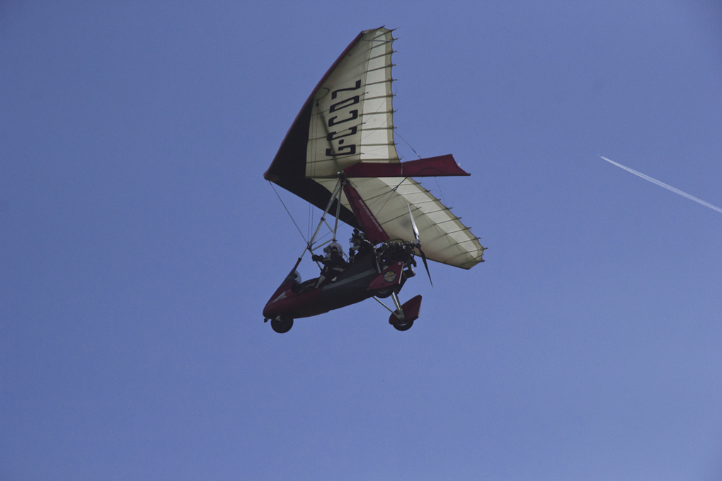 Microlight mid flight set against a blue sky.