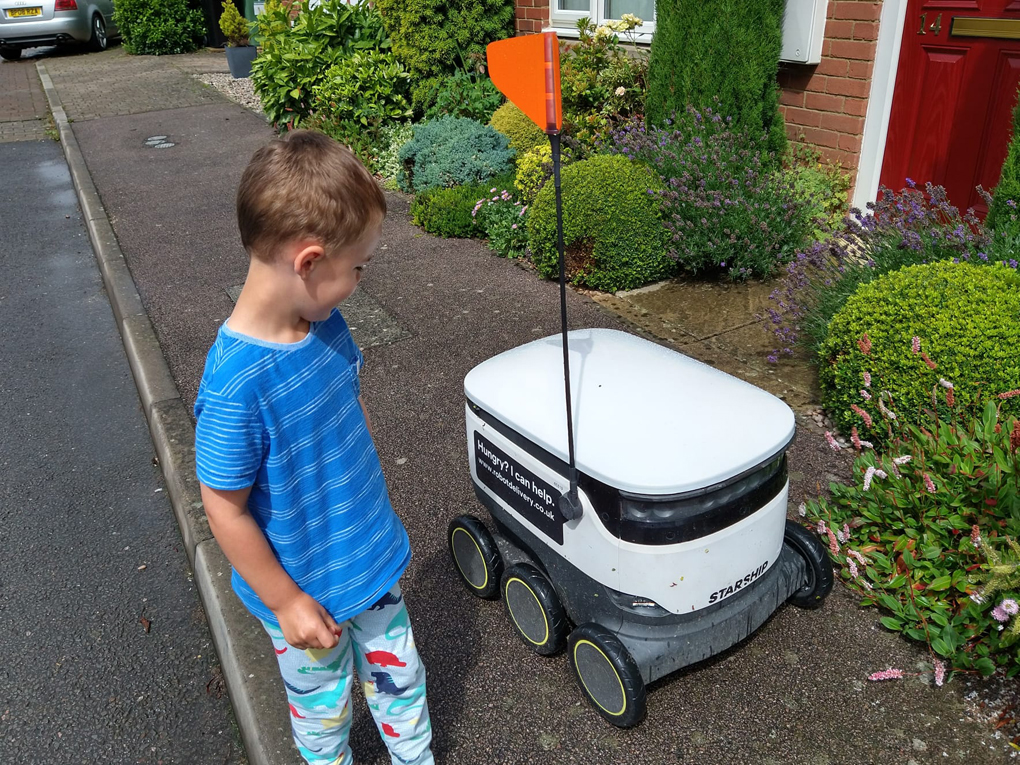 Boy looking at a white square wheeled robot
