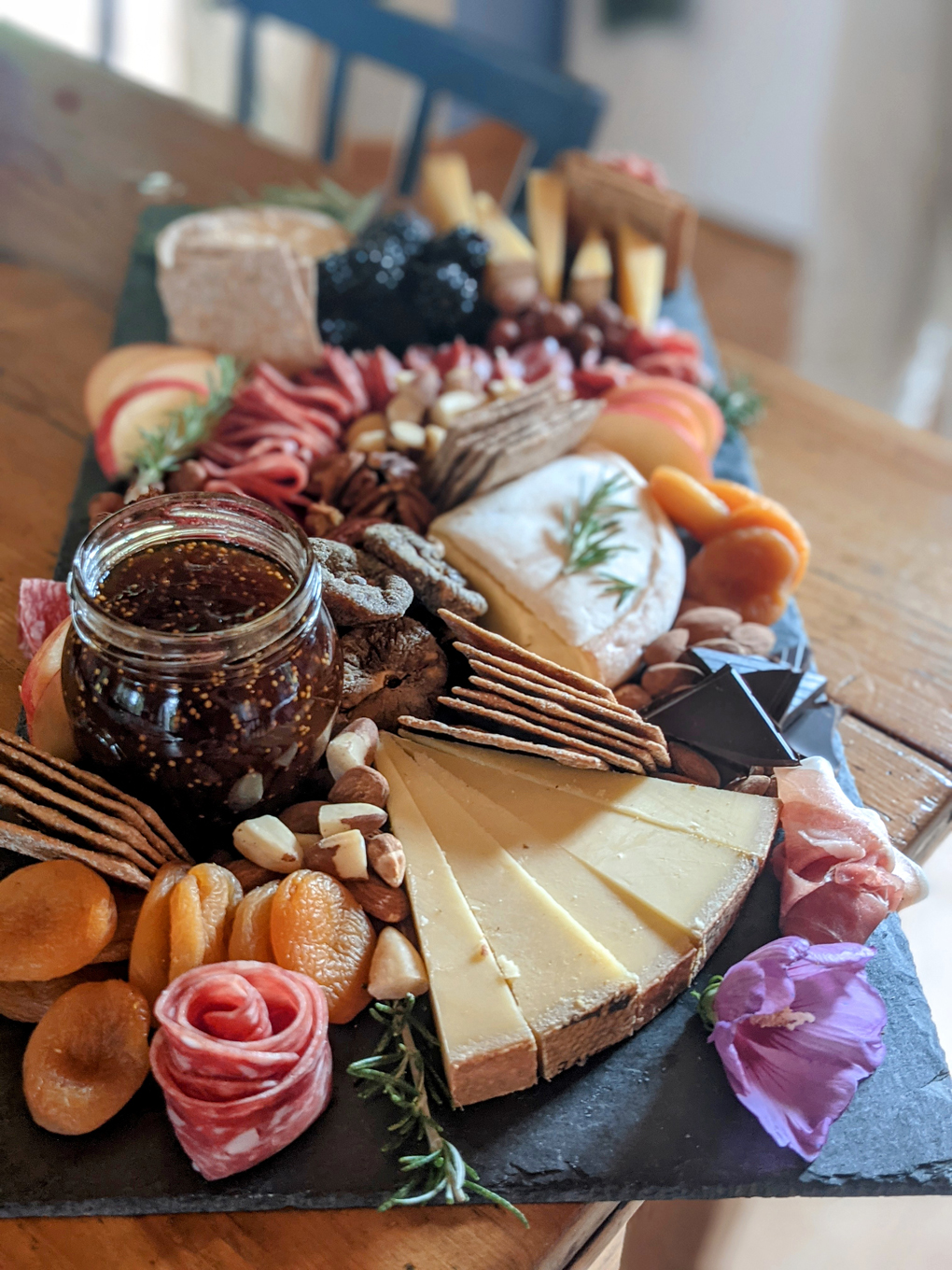 Cheeses, nuts, fruit Nd flowers on black slate