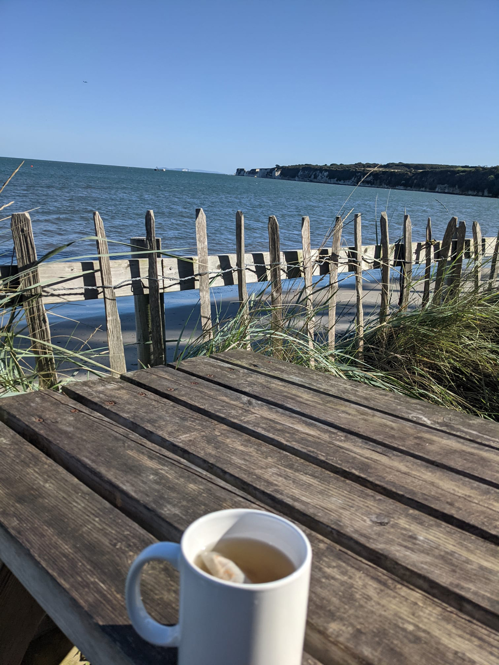 Tea in a mug on a bench in front of the sea