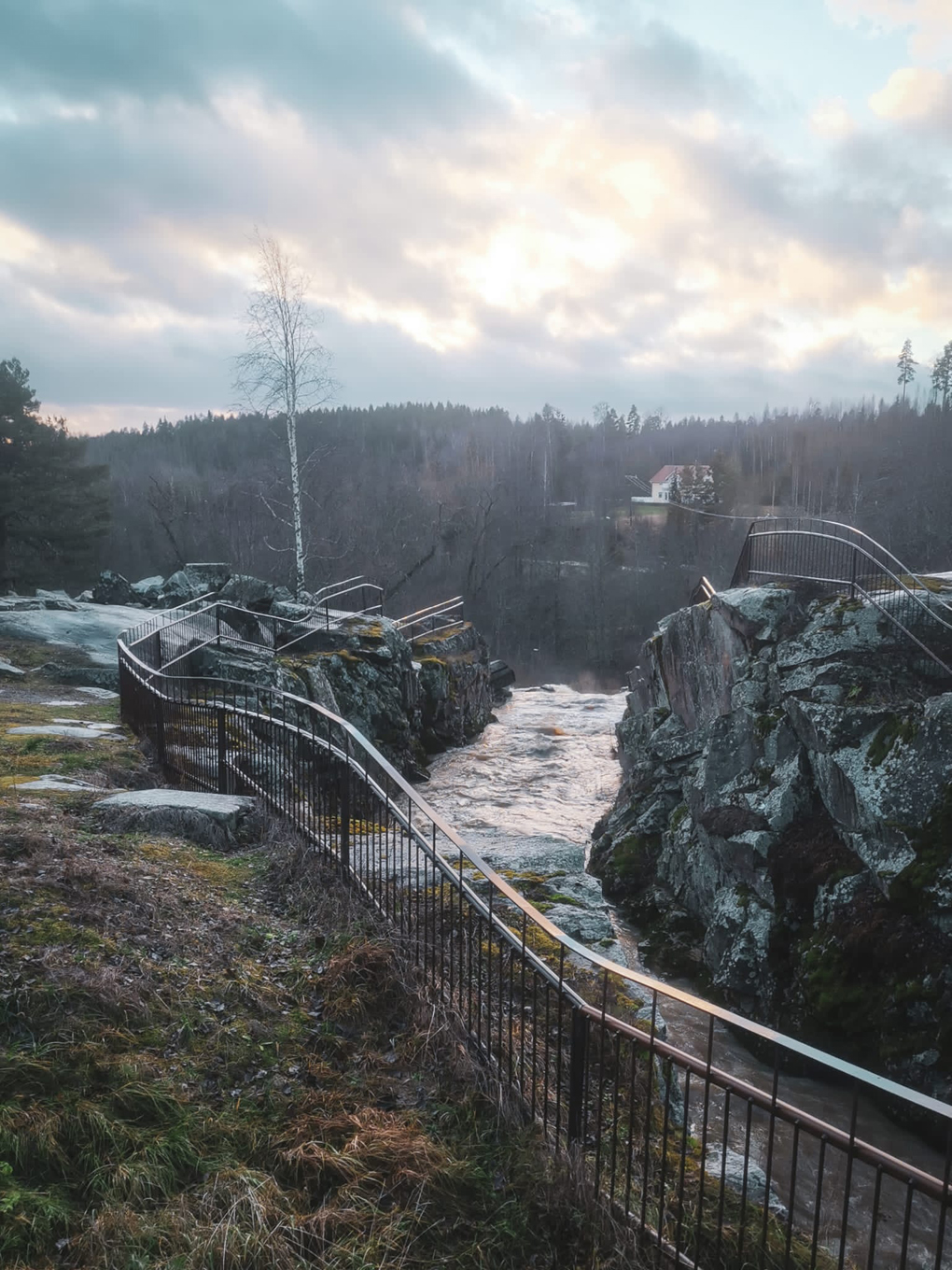 Cloudy sky, rocks, and water running towards a fall.