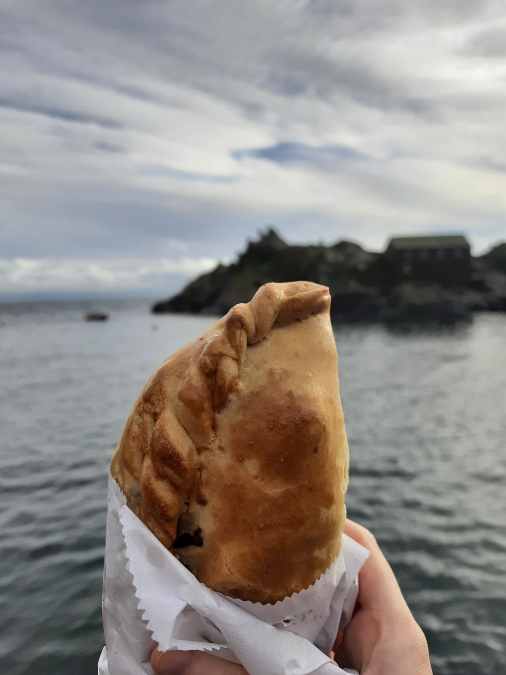 A Cornish pasty against with the sea in the background