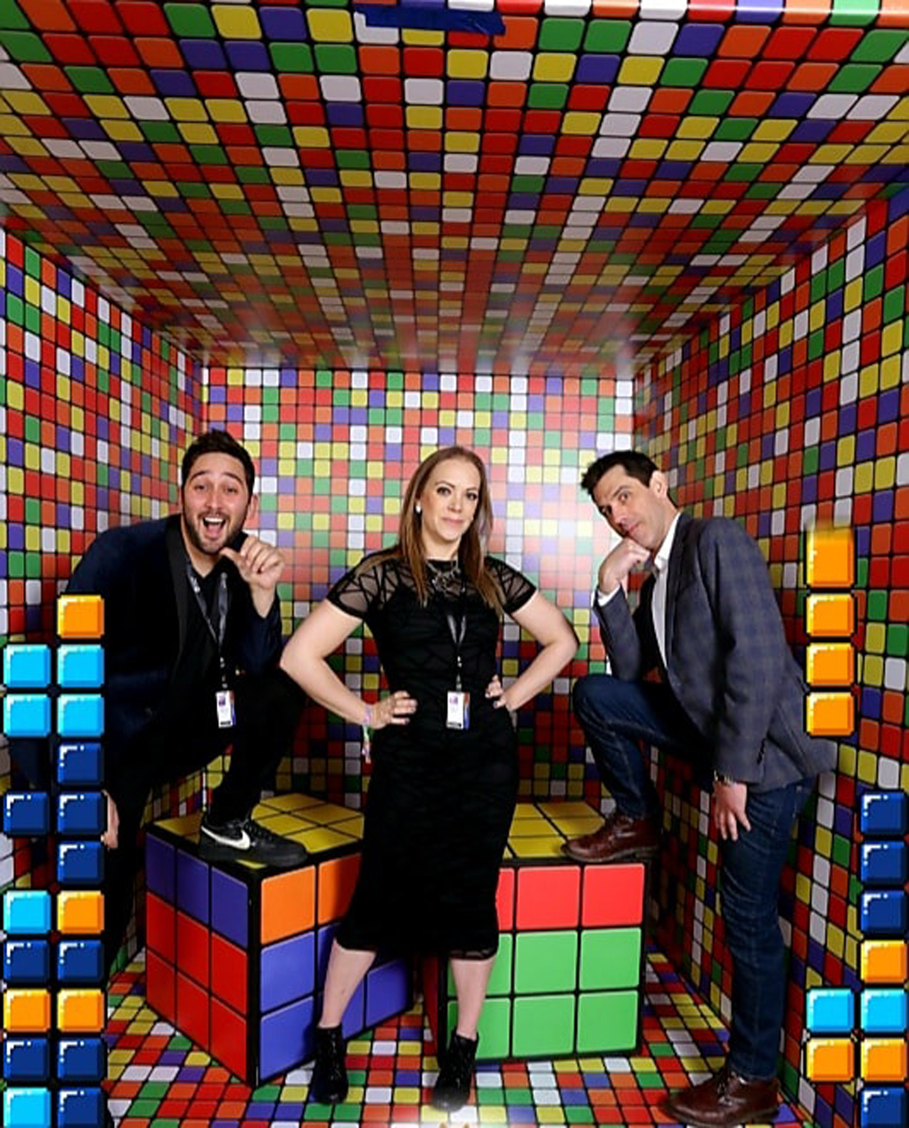Three people standing in a room filled with rubik's cubes