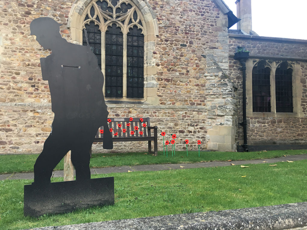 WW2 memorial consisting of a large metal soldier and fake poppies stuck into the surrounding ground