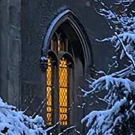 A church with a lit up window against a snowy background