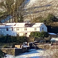 A view of hills, fields and trees, all lightly dusted with snow, under a clear sky