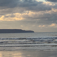 Portrait of clouds reflected in water on Westward Ho! beach at sunset.