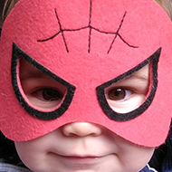 A baby wearing a Spiderman mask