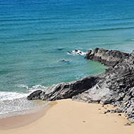 Taken from a cliff top, a sandy cove with bright blue waters and yellow sand