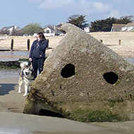 The remains of a concrete  barge lying on its side on a sandy beach