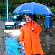 lady in a raincoat standing waist-deep in water in front of a 