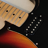 A part-built sunburst and black Fender Stratocaster on a workbench