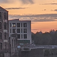 Sunset over the river Avon in Bath. Mix of urban building, greenery along the river and water mirroring the sky