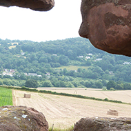 Archer's eye view looking east from Goodrich Castle over the rolling countryside, with the River Wye is in the fold of the hill. The arrowslit or loophole is a narrow vertical opening in the stonework through which the archer can loose his arrow.