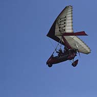 Microlight mid flight set against a blue sky.