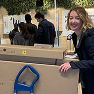 Woman pushing trolley of large flat pack boxes