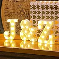 An underground wine cellar, with some large barrels in the background. In the foreground there are the letters J and K lit up in lights.