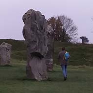 A section of the Avebury stone circle framed by green grass and a cloudy sky.