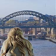 People look out over the Tyne river and bridges from a large glass viewing gallery high in the Baltic Arts Centre