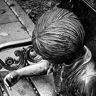 Metal statue of a girl and her dog on a bench.