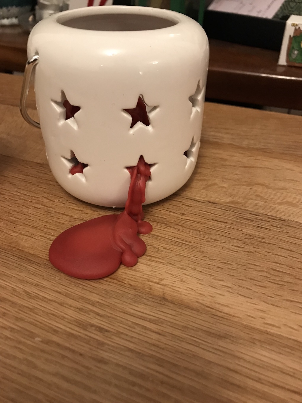 Red candle wax squeezing through a star shaped hole in a lantern.