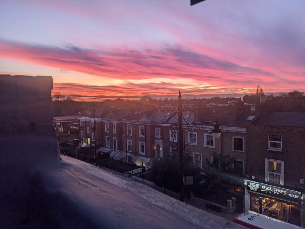 Sunset of pink and orange and clouds over buildings