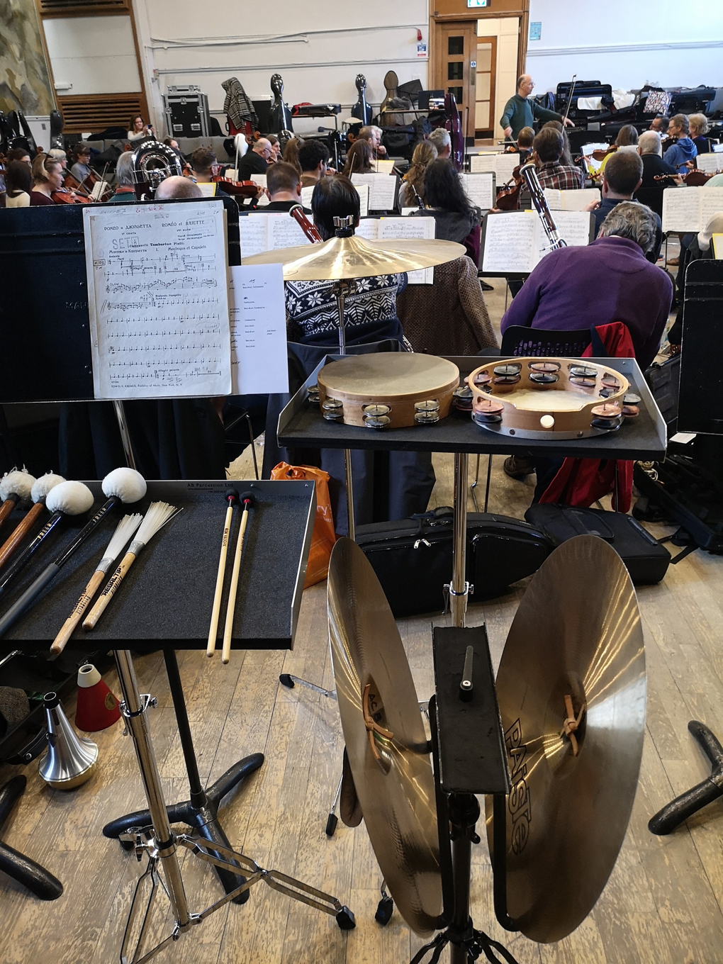 A view from the back of the orchestra showing cymbals and music stands.
