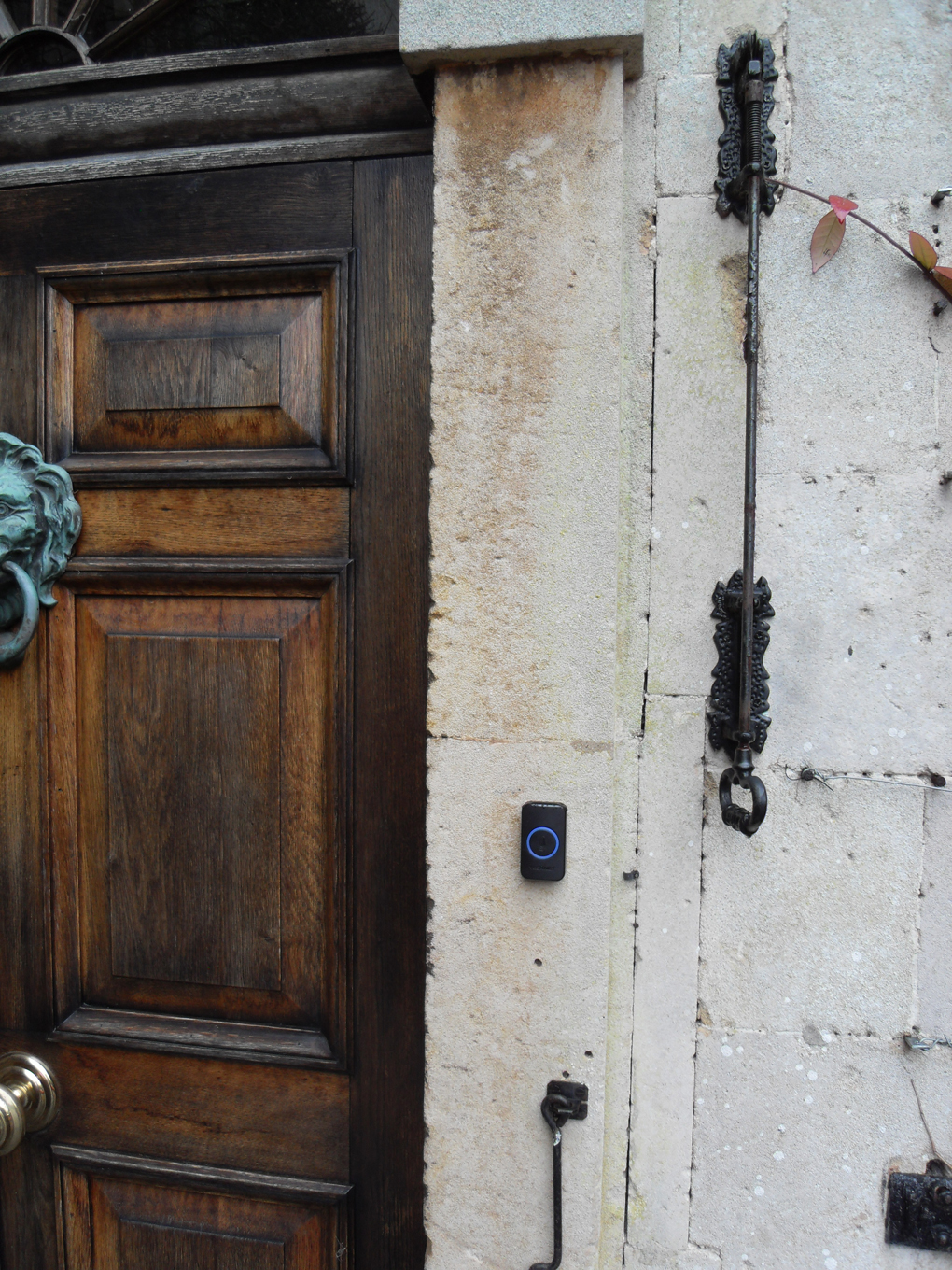 Original georgian doorbell and modern phone-linked doorbell on stone wall