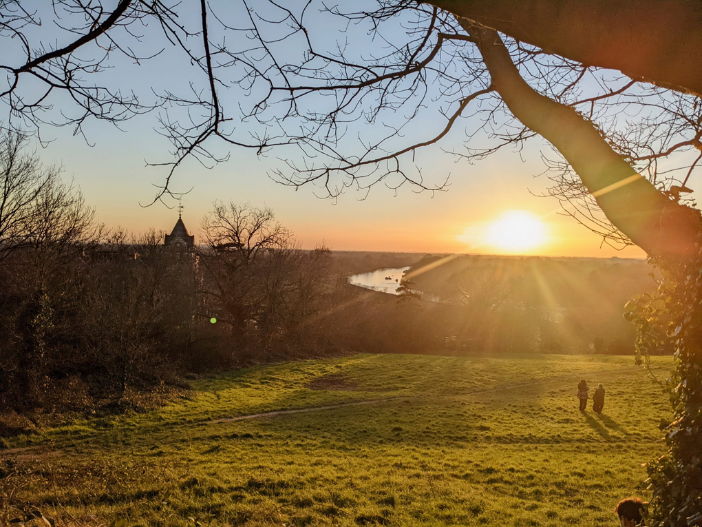 Sunset over river, Petersham hotel, two people walking on grass area