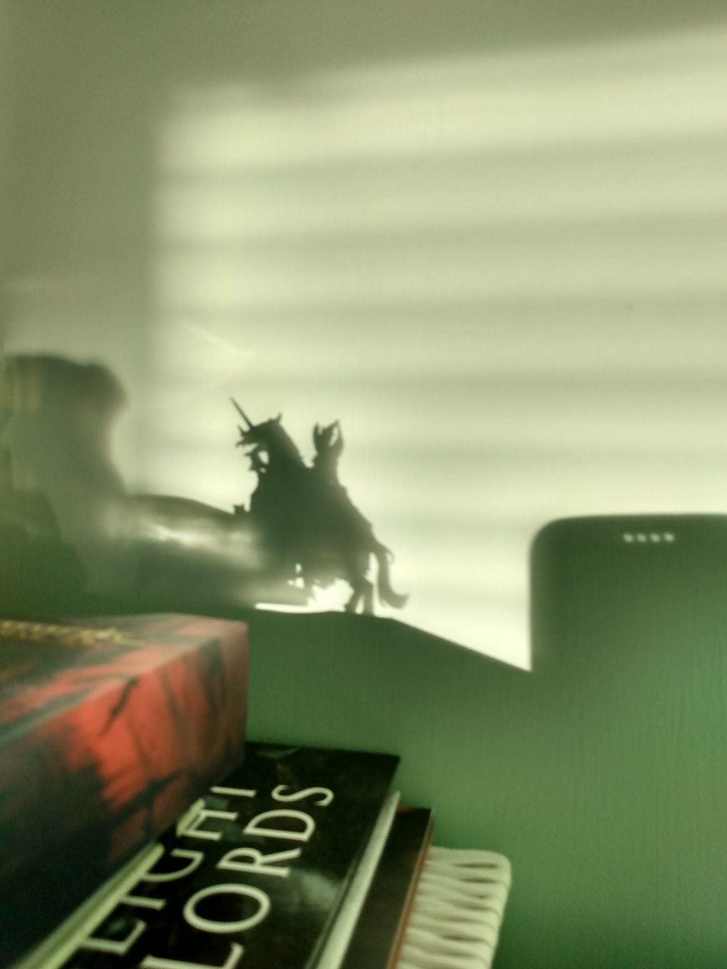 A shadow on a green wall of a wargaming miniature on horse, rearing up