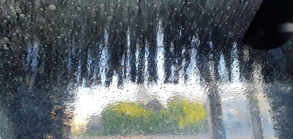 In a car wash, the brush is halfway down the front windscreen, with water cascading down the screen
