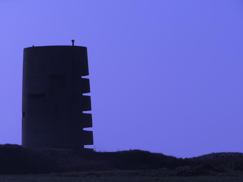 We see the silouhette of a restored WW2 five story observation tower, part of the German fortifications on Guernsey