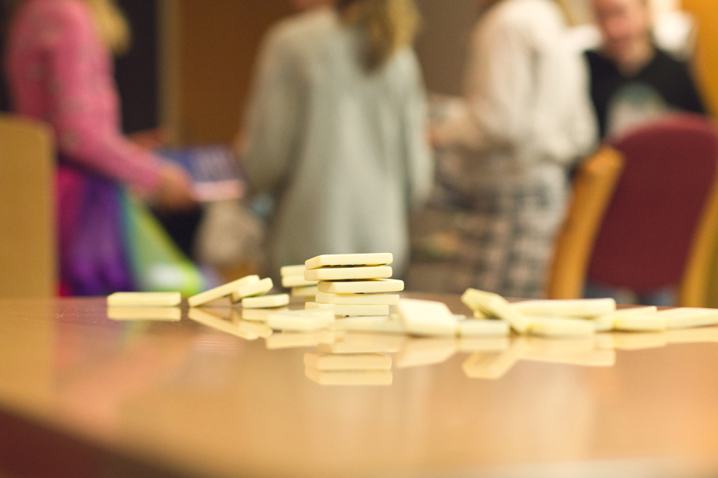 Fallen dominoes resting and reflecting on a wooden table.