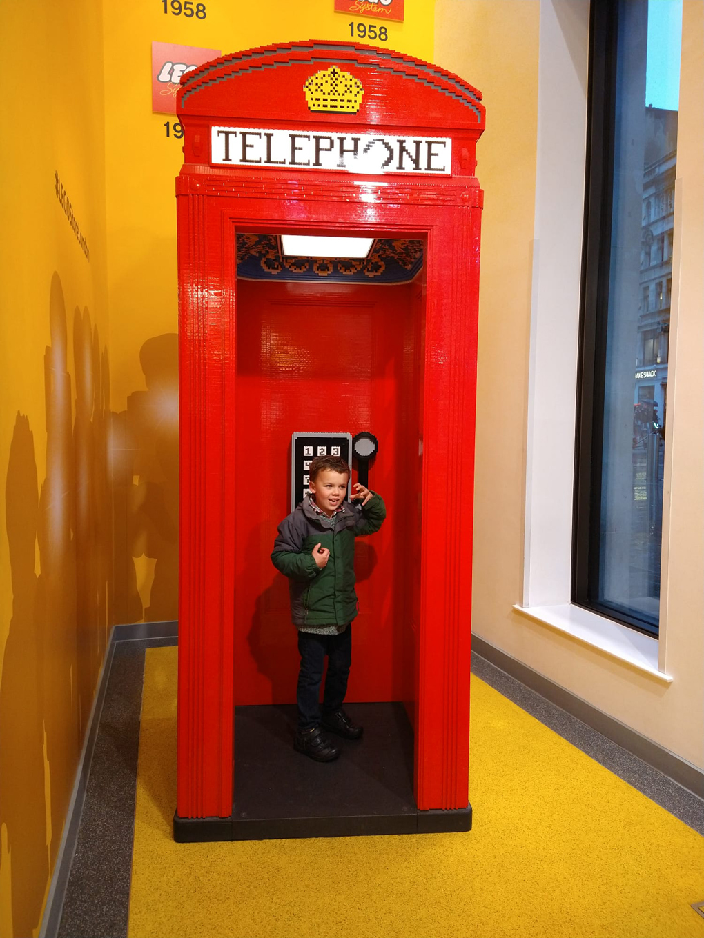 small boy in lego phone box
