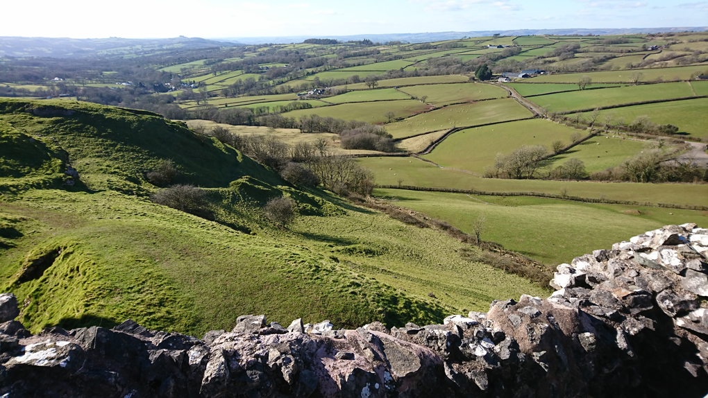 Beautiful view of  part of The Brecon National  Park from the outer walls of Castle Carreg Cennen - a lush green slightly undulating landscape with some mountains far distant. The castle built on a steep craggy outcrop was part demolished during The War of the Roses sadly but is still an interesting ruin to visit, making for a lovely afternoon of exploration.