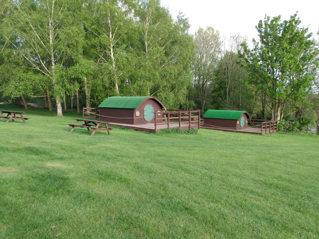 Some small brown huts with round, green doors