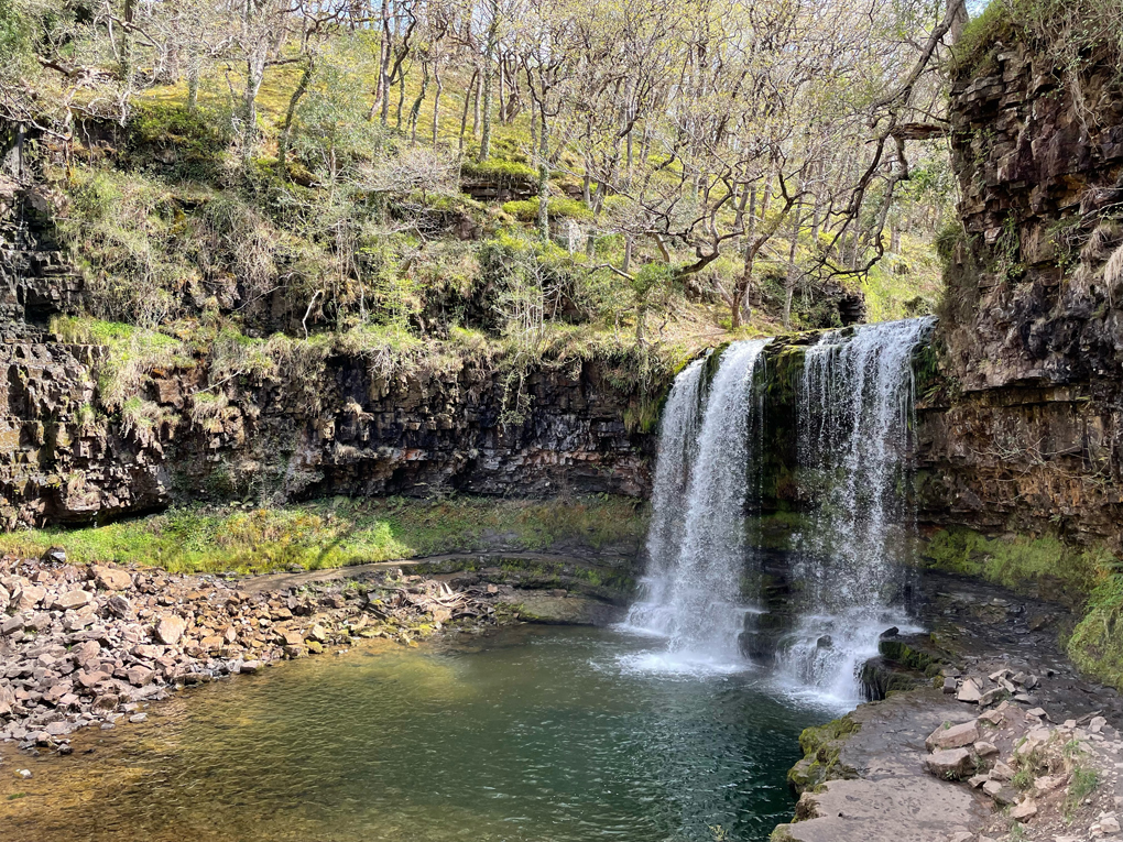 A waterfall in a Welsh forest running into a clear water pool